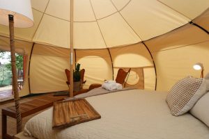 Glamping shot of bed and seating area in large tent